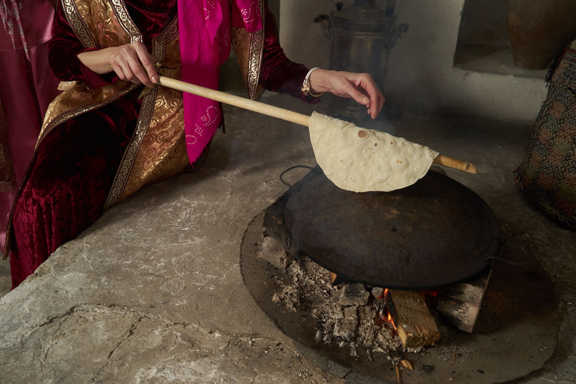 Woman hands cooking Pita bread on fire, close-up, indoors