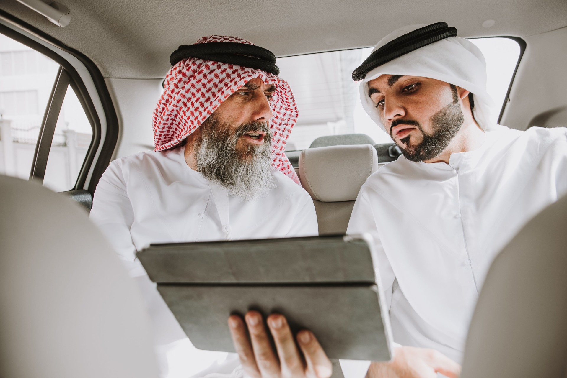 Business People Discussing Over Digital Tablet While Sitting In Car